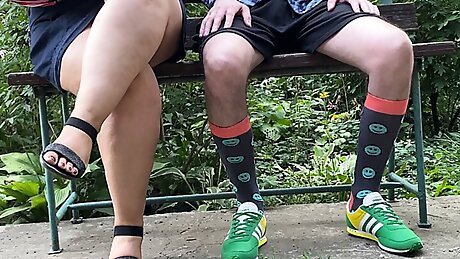 Luxurious stepmother helps her stepson to pee while sitting in the park on a bench